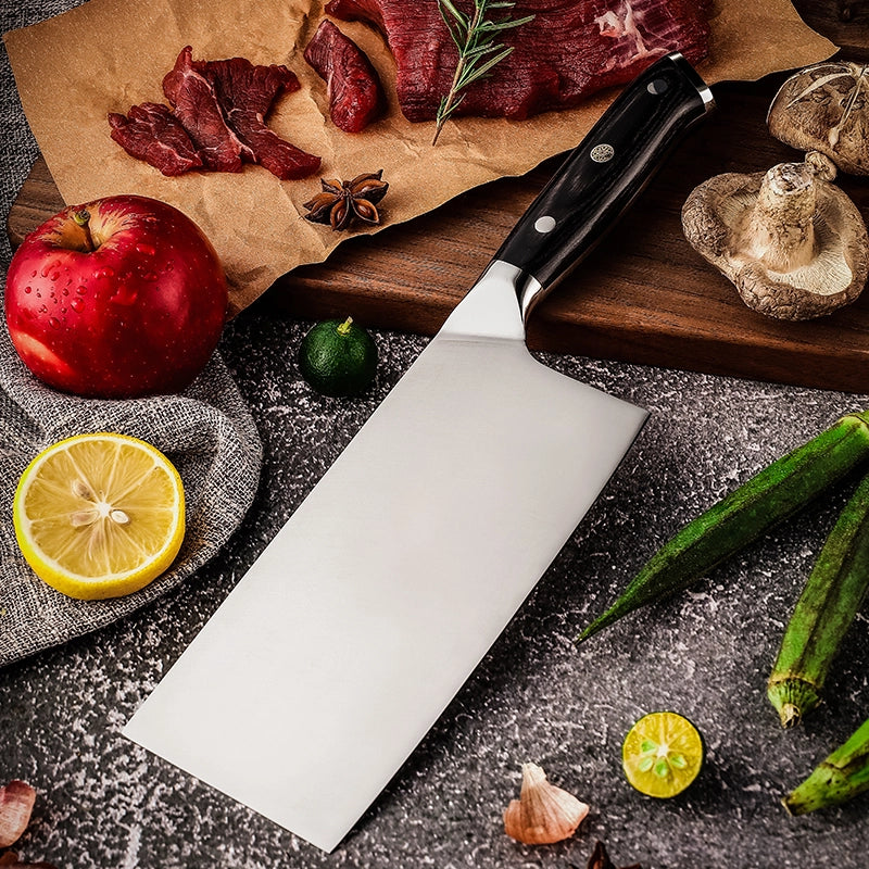 Knife on a dark surface with ingredients like apples, lemons, and okra.