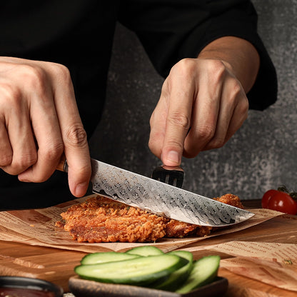 Person cutting fried food with a knife on a wooden board, surrounded by sliced cucumbers and a tomato.
